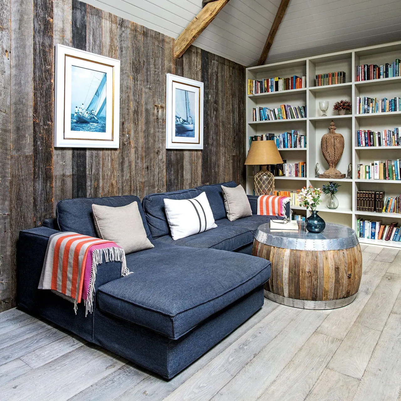 A blue sectional sits beside weathered-looking timber walls and a round wood table.