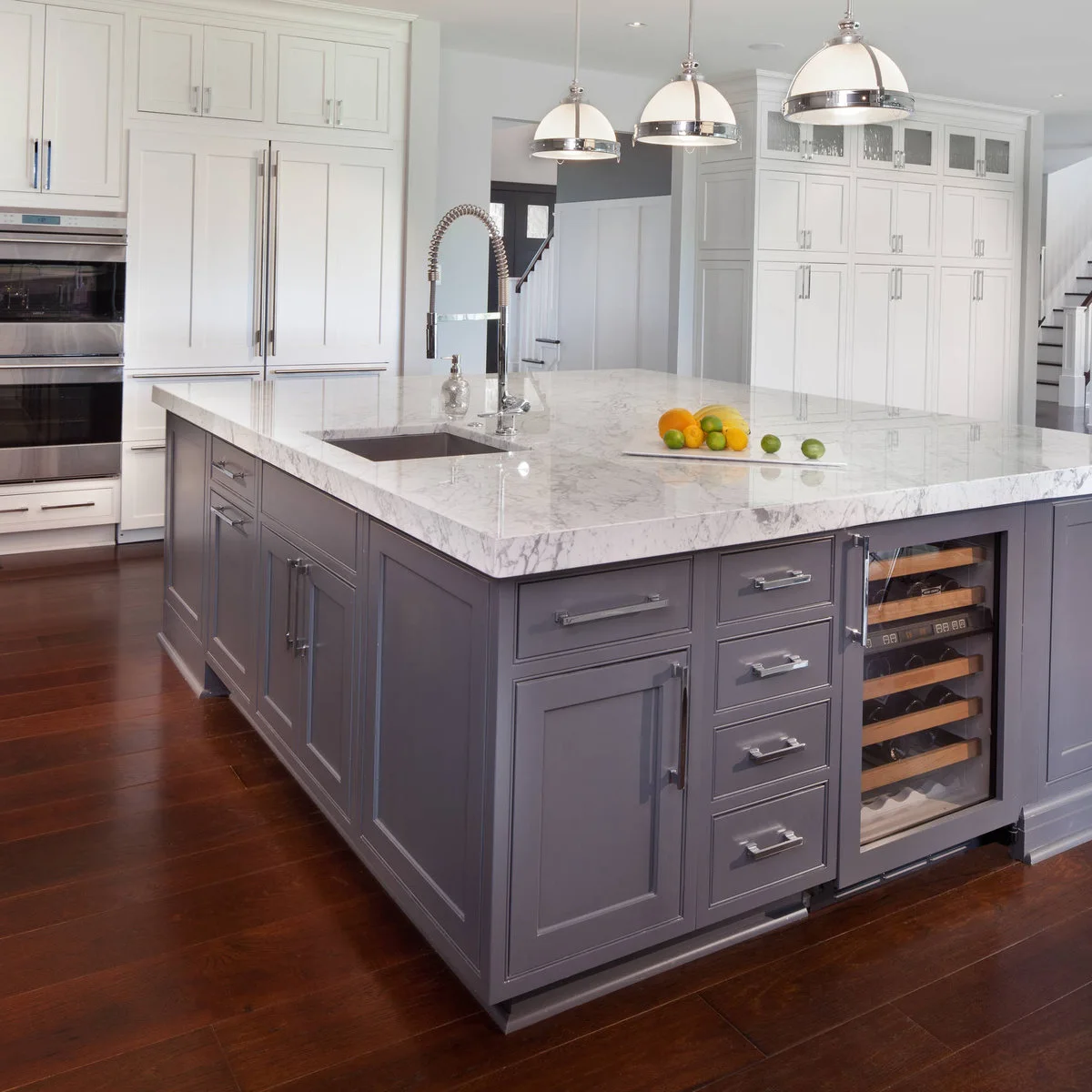 Gray kitchen island with a glass-front beverage cooler beside a bank of drawers