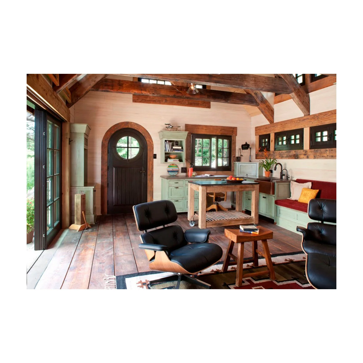 Compact open sitting area with two black lounge chairs, wood-colored floor and pale green cabinets