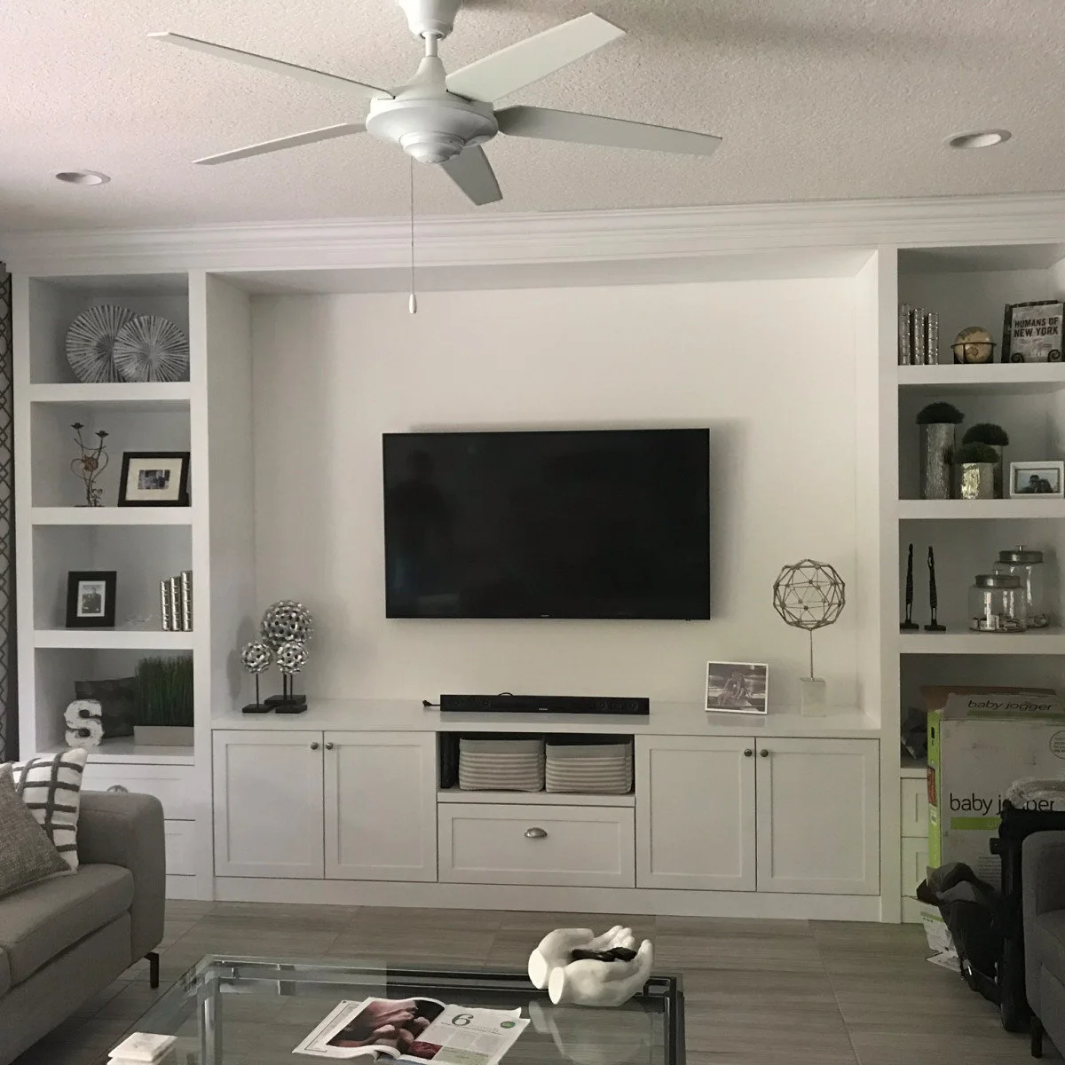 White built-in TV wall with open side shelves, base cupboards and two storage baskets