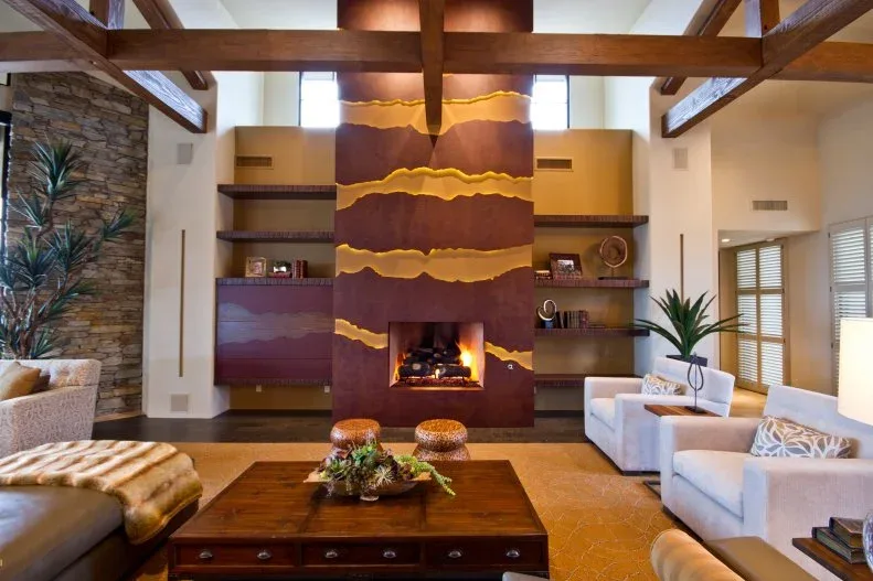Warm brown fireplace wall with irregular gold-toned horizontal bands, display shelves and pale chairs