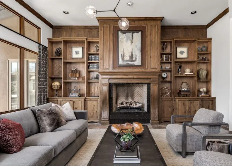 Warm wood fireplace wall with open shelves, lower cabinets, central picture and gray seating