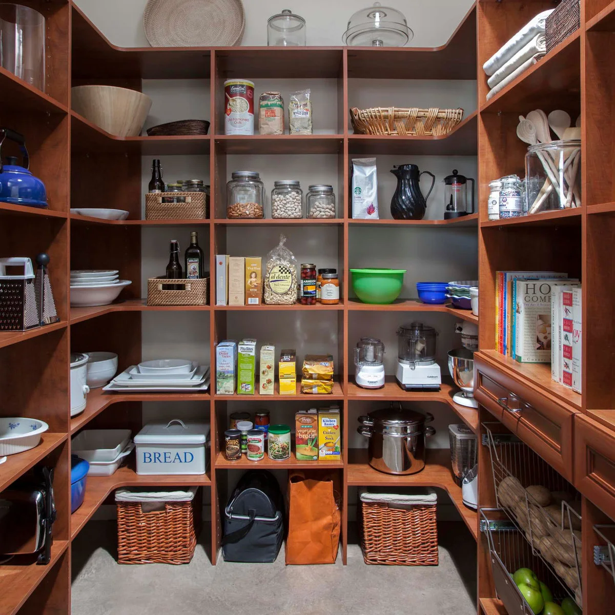 Wooden pantry shelving with rounded corners, food jars, cookware and baskets