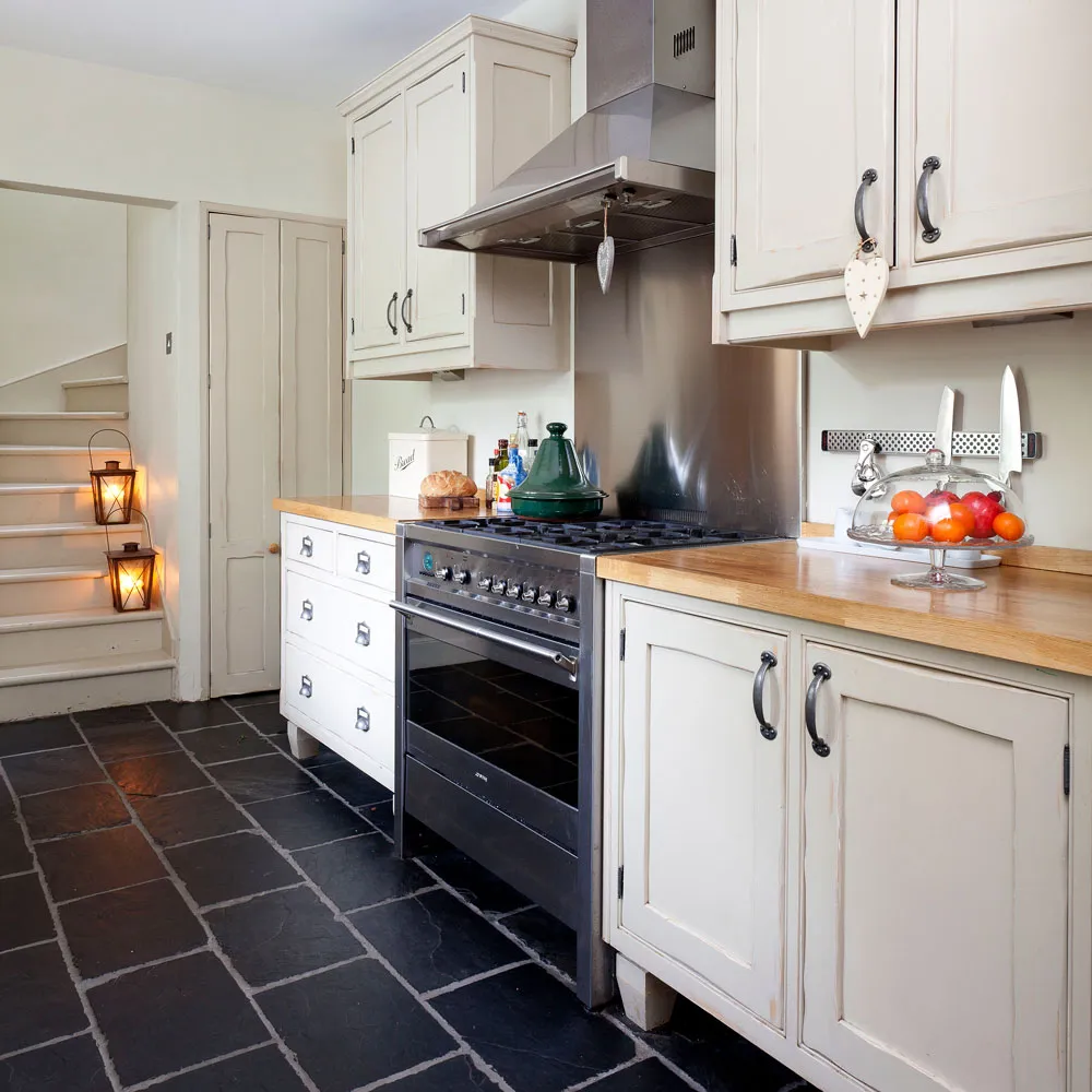 Cream paneled doors sit above a dark tiled floor beside a range