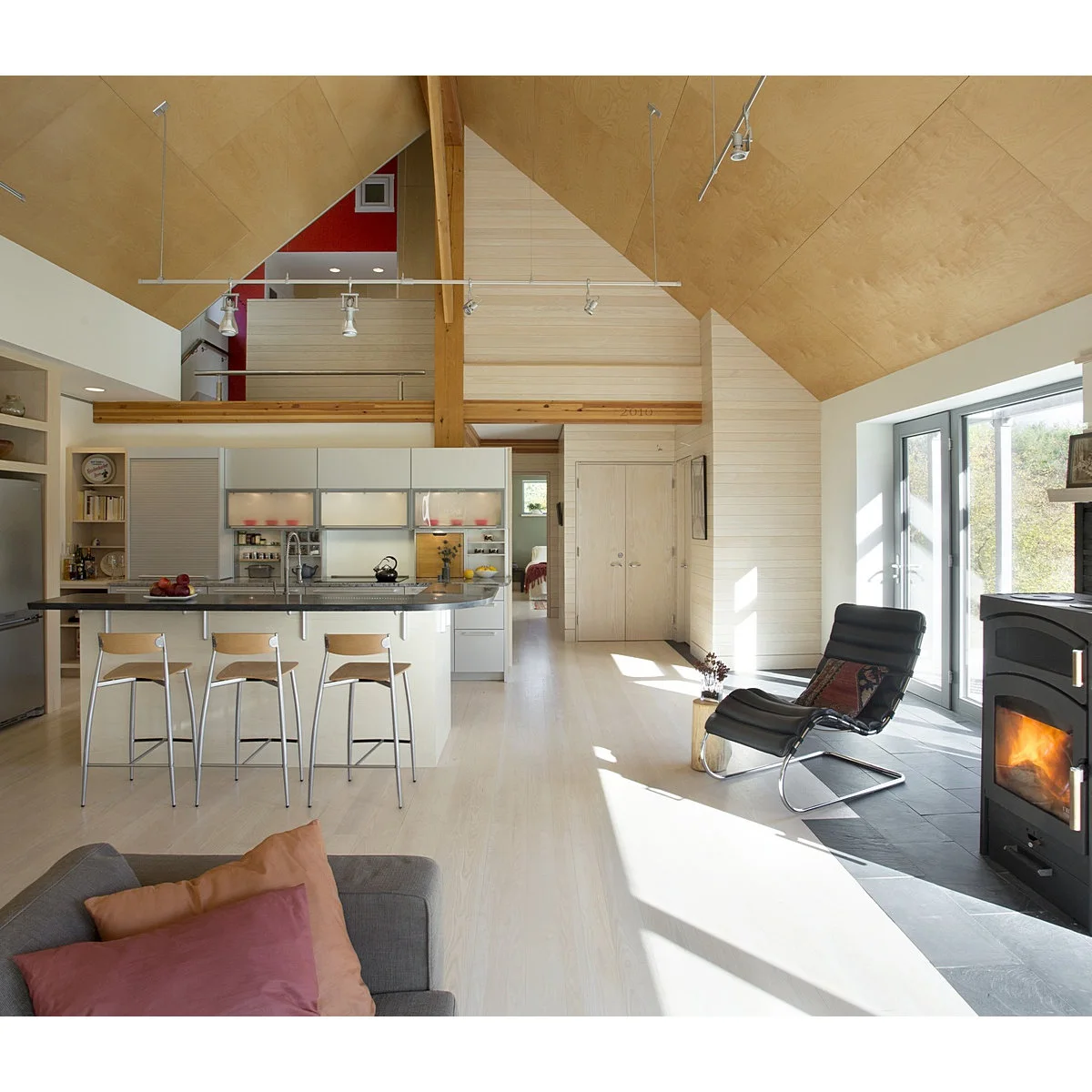 Large pale wood ceiling panels above a white open kitchen and living space