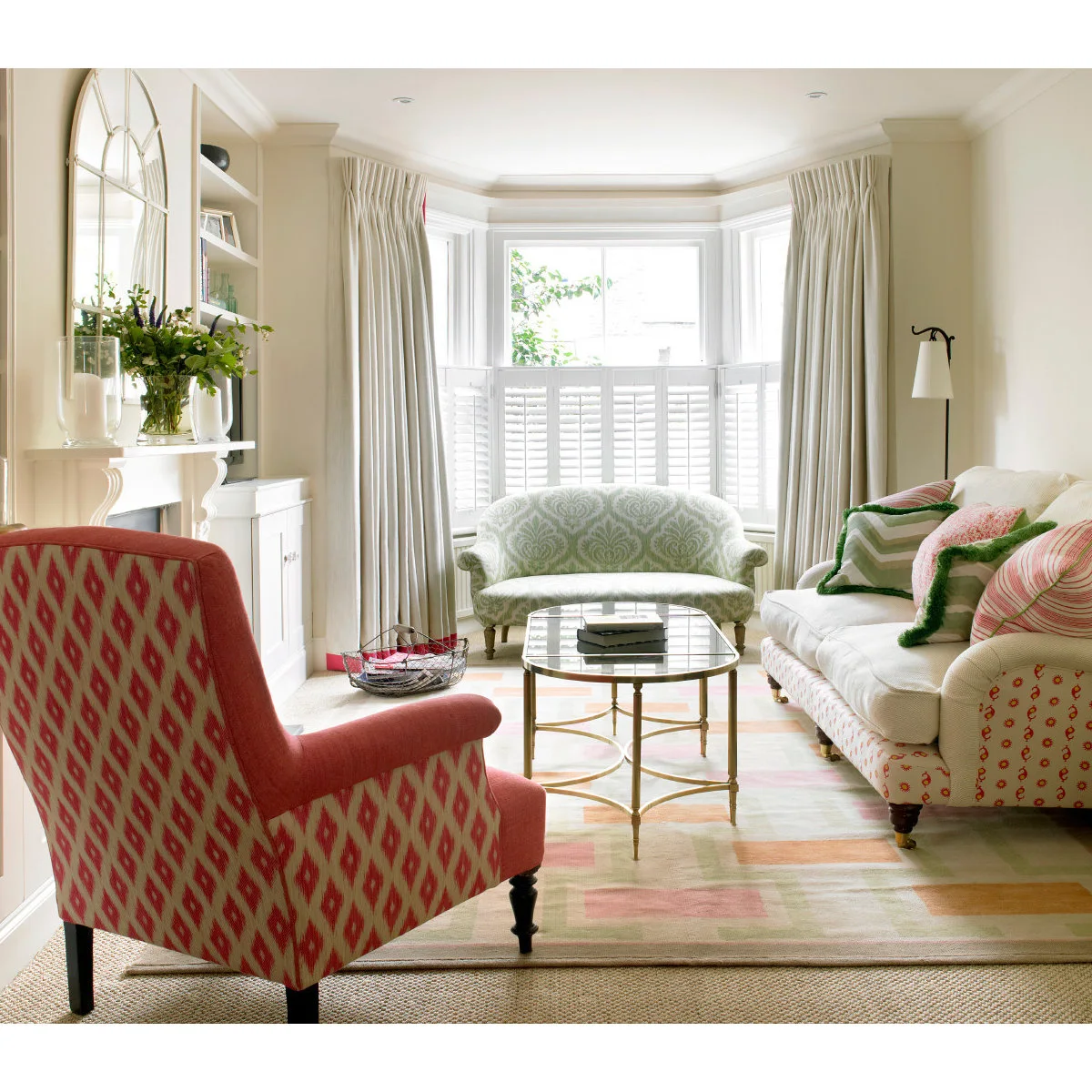 Battersea terrace living room with a pale sofa, red chair, curved bay seat and oval glass table