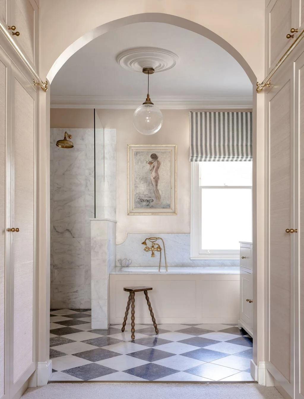 A low pale wall topped with clear glass separates a doorless shower from a bathtub above a gray and white checkerboard floor.