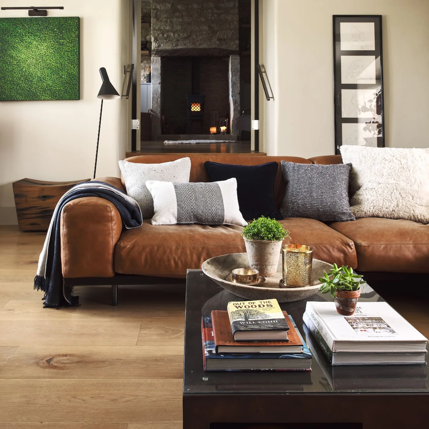 Brown couch with large pale textured pillows, dark gray squares and a small pale rectangular pillow.