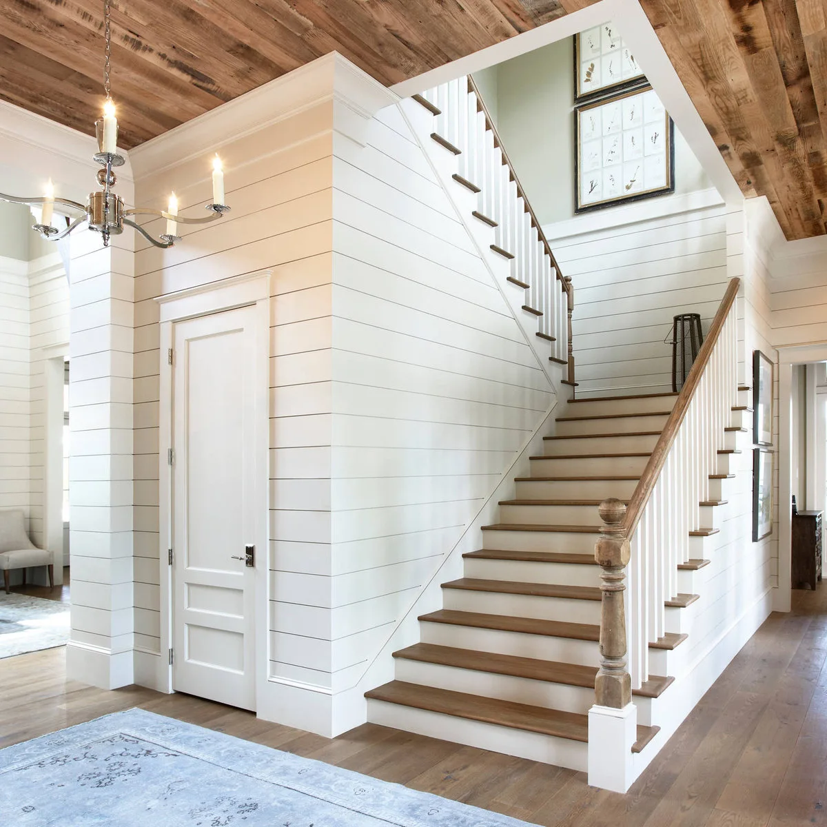 Wood and white staircase with horizontal wall boards and a plain white door below the flight