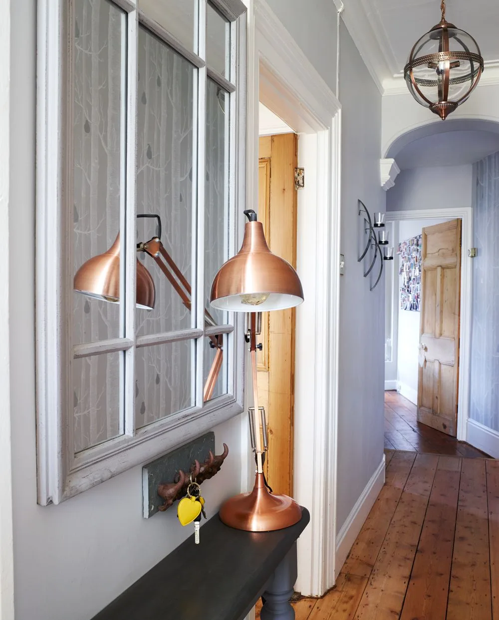 Traditional narrow hallway with an arched opening, framed mirror, copper-colored lamp and ceiling lantern.