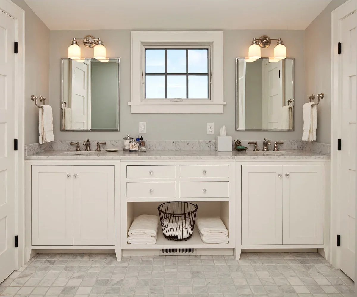 Matching curved metal holders carry white towels on the side walls at either end of a pale double vanity beneath rectangular mirrors.