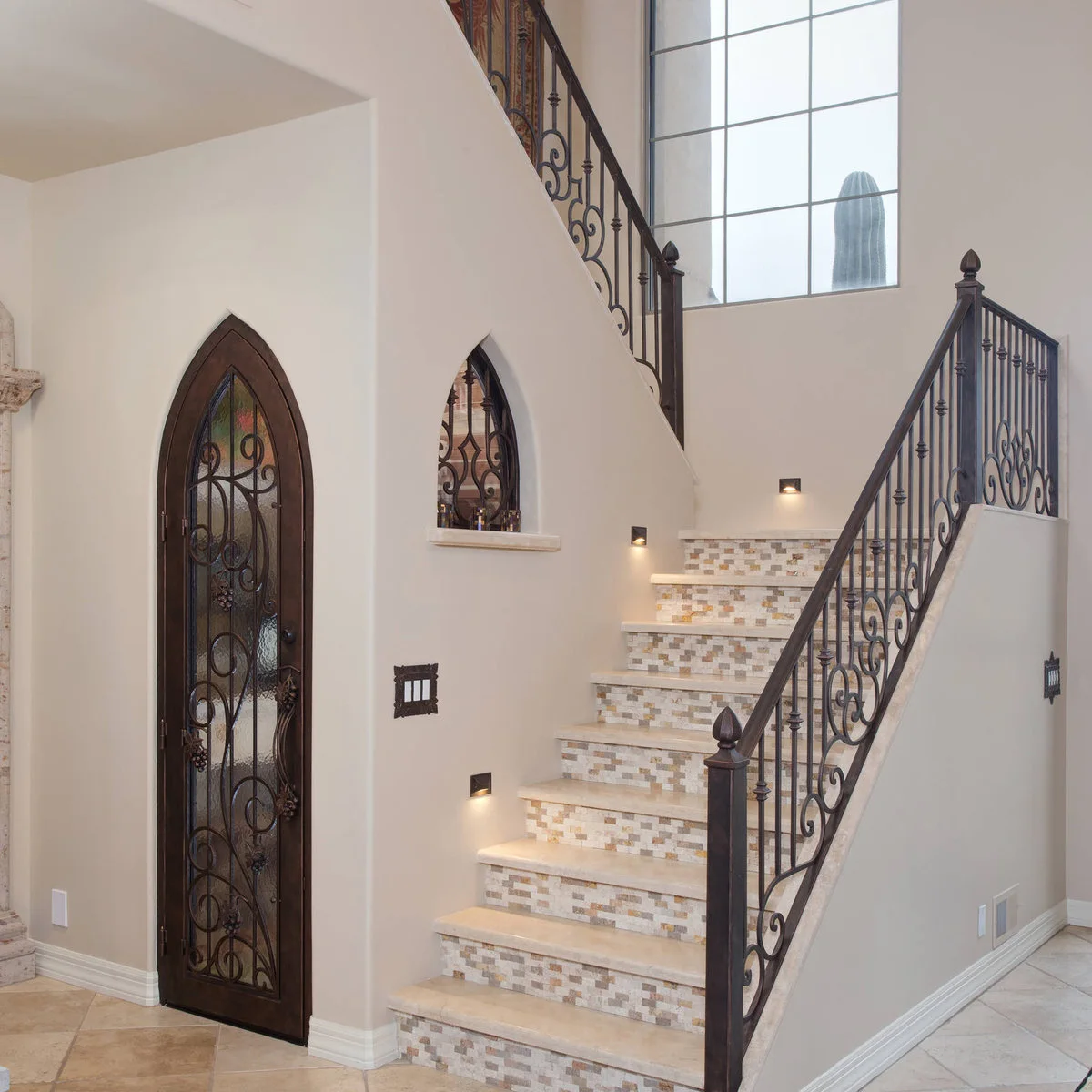 Staircase with small warm mosaic tiles on the risers, pale treads and recessed wall lights