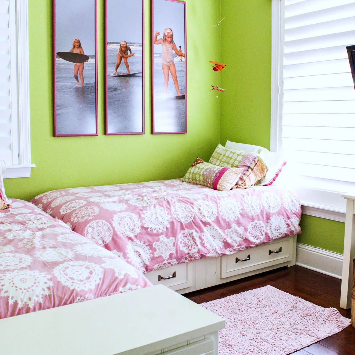 Compact sleeping room with white drawer-bed bases, pink patterned bedding and lime green walls