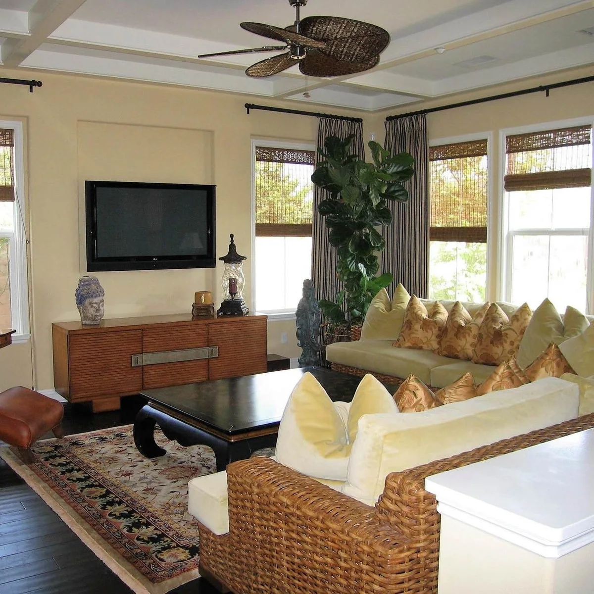Light sitting room with woven sofas, yellow cushions, striped curtains and a television above a low wood cabinet