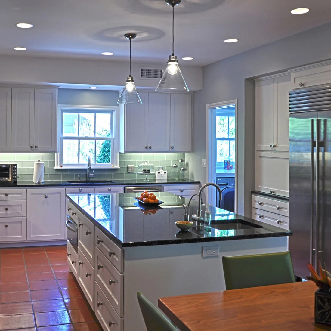 Red square floor tiles run around a white kitchen island beneath reflective dark counters.