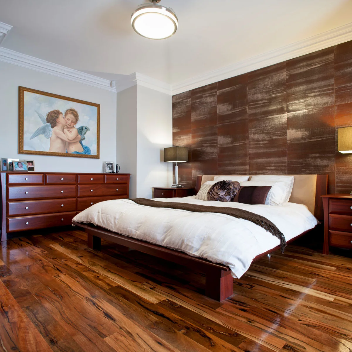 Shimmering brown wall behind a wooden bed with white bedding and reddish-brown dressers.