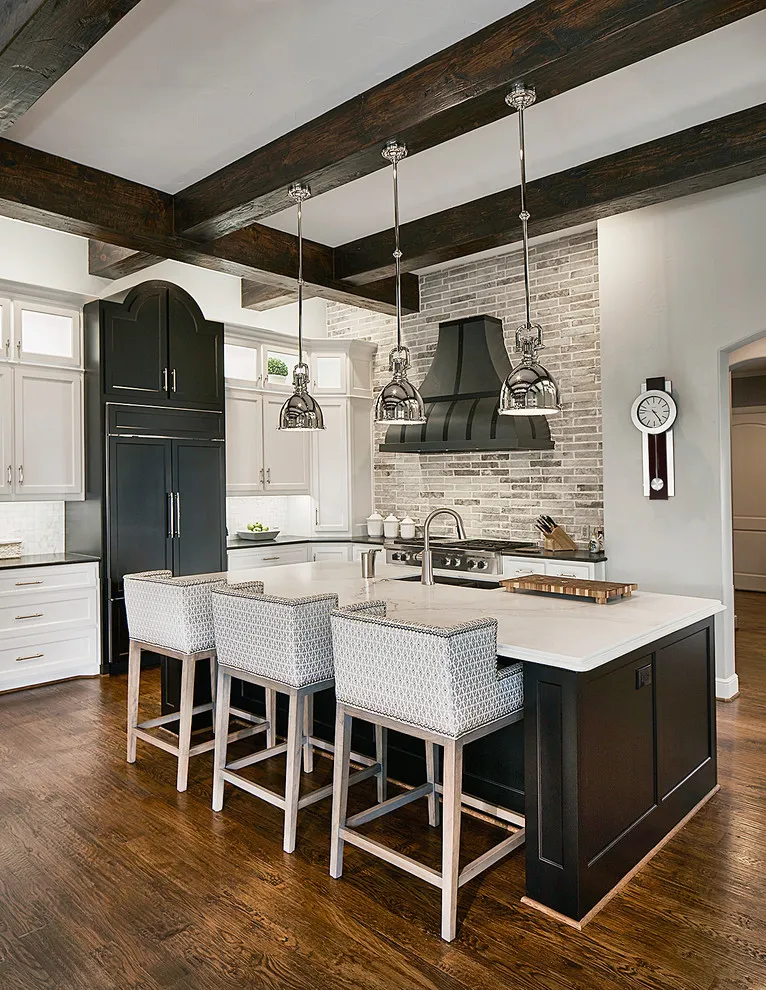 A dark island sits below a pale counter and timber ceiling beams