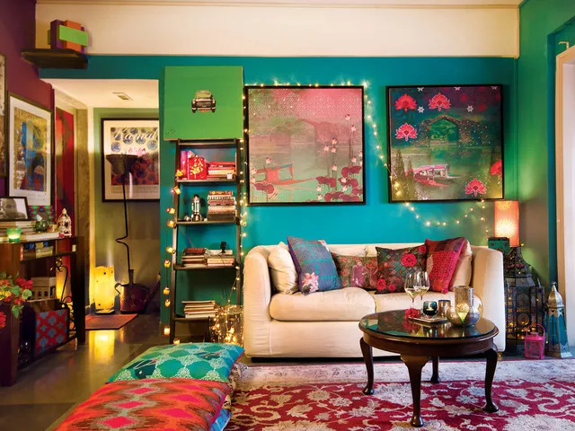 Green walls frame pale seating, colorful art and a warm timber side table.