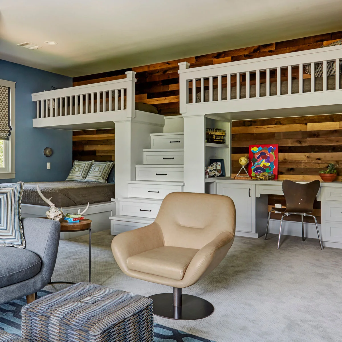 White built-in raised beds with central drawer stairs, a lower bed on the left and a desk on the right against wood paneling.