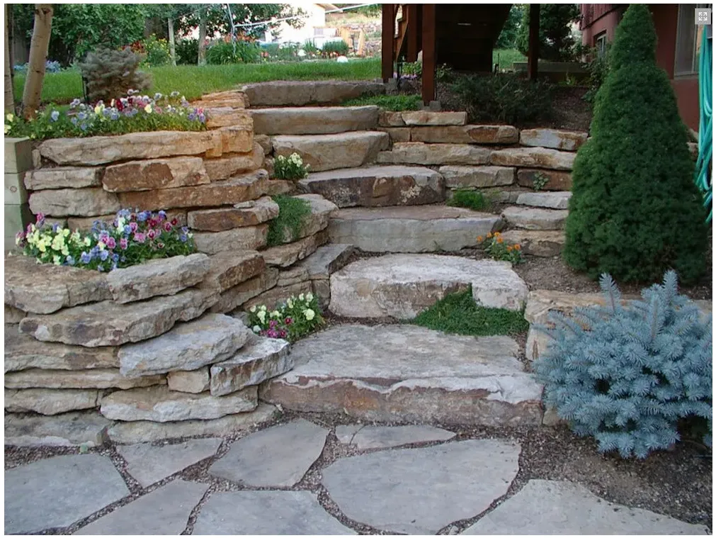 Irregular garden steps pass between stone retaining edges and pockets of flowering plants.