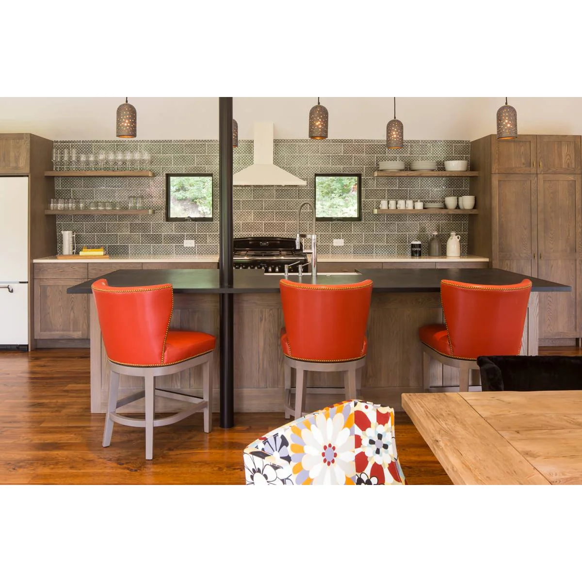 Orange-red upholstered kitchen stools with curved backs, pale legs and circular foot rails