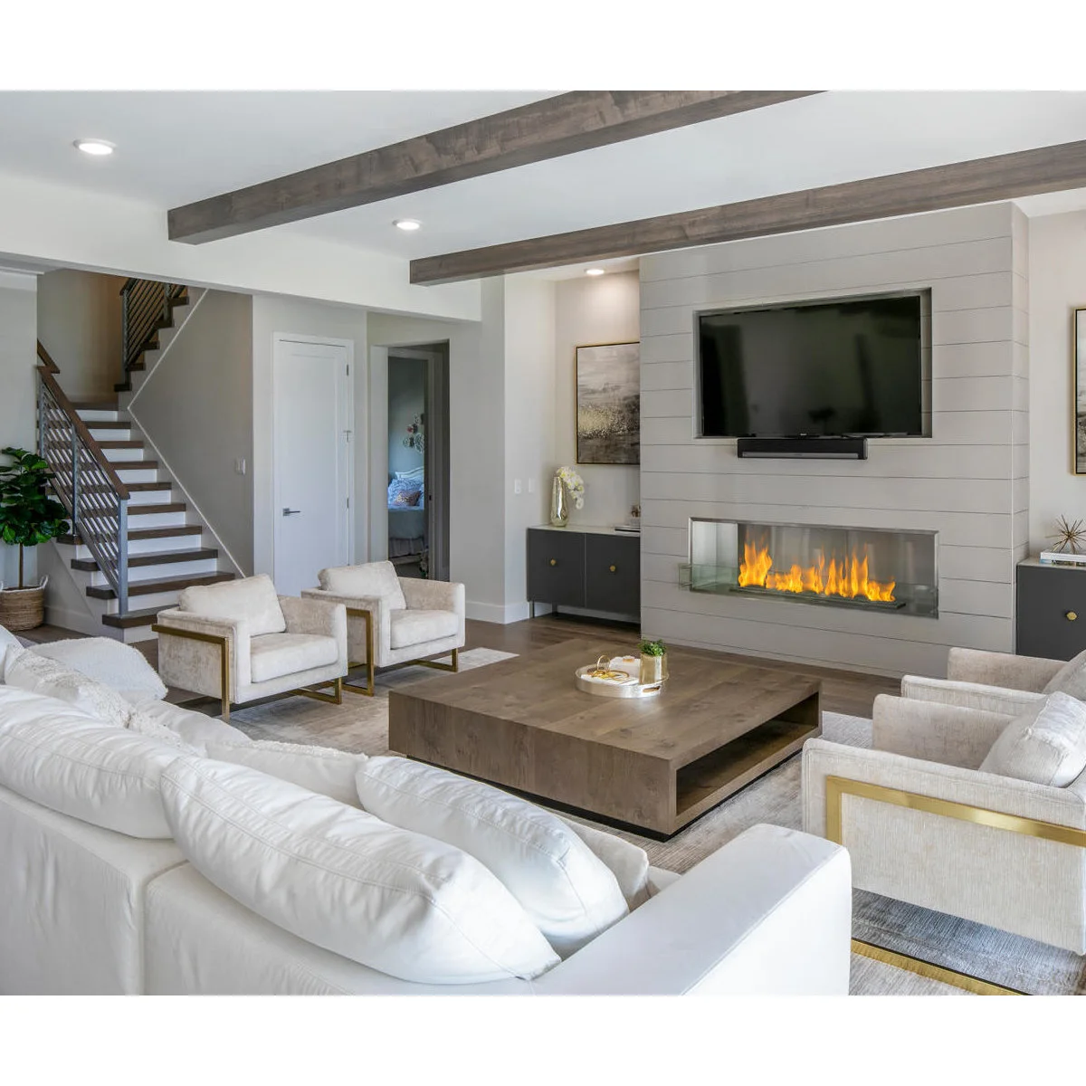 TV above a linear fireplace on a pale horizontally paneled wall with low side cabinets