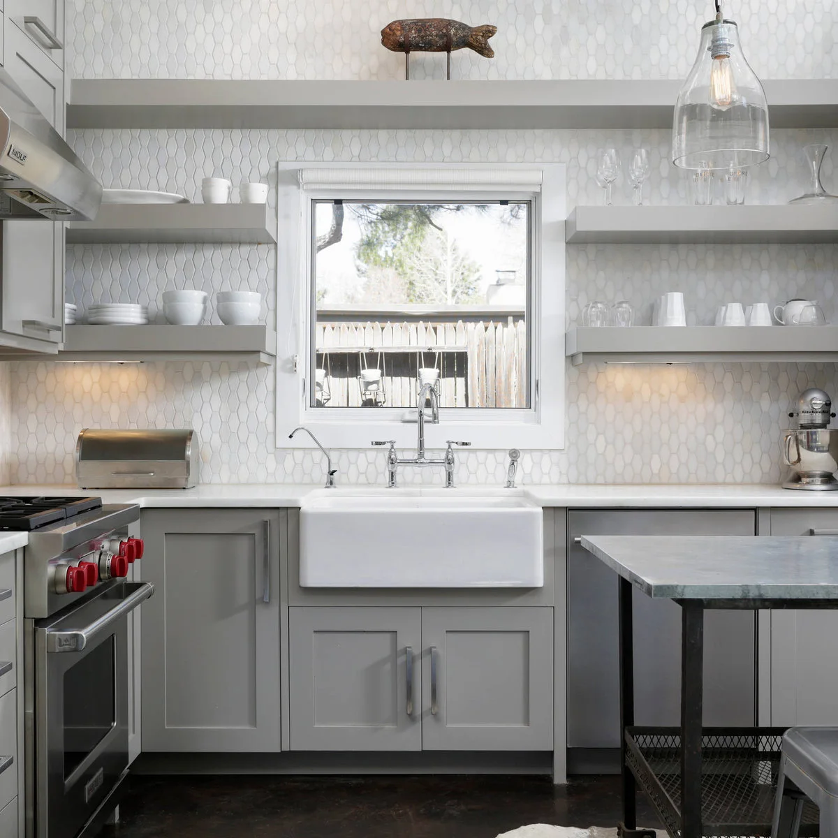Gray shelves flank a small white-framed kitchen window, with one long shelf high above it.