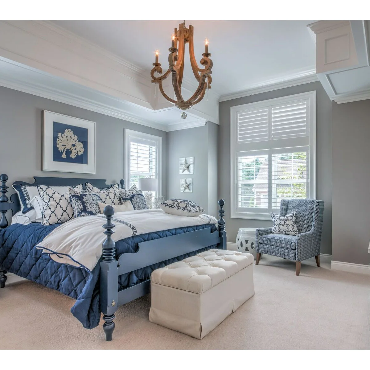 Grey bedroom walls with a blue bed frame, white shutters and blue patterned bedding