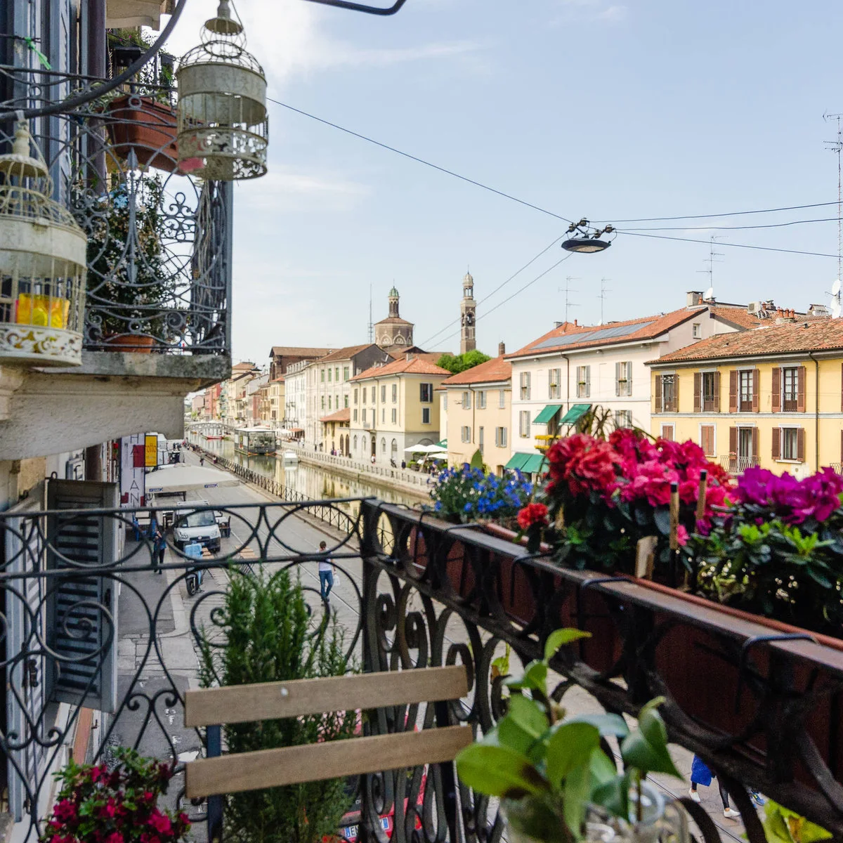 Narrow apartment balcony with flower containers, decorative railing and wood-colored chair
