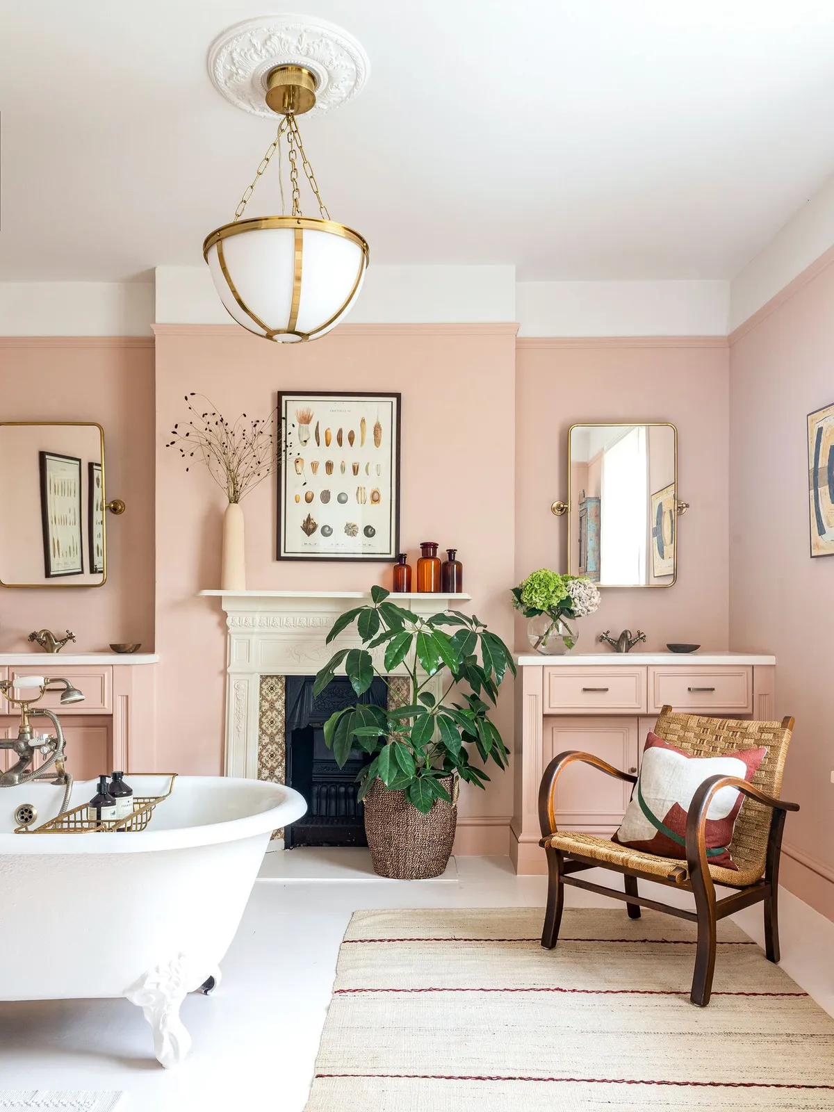 Pale pink walls surround a basin, bath and small timber-framed chair.