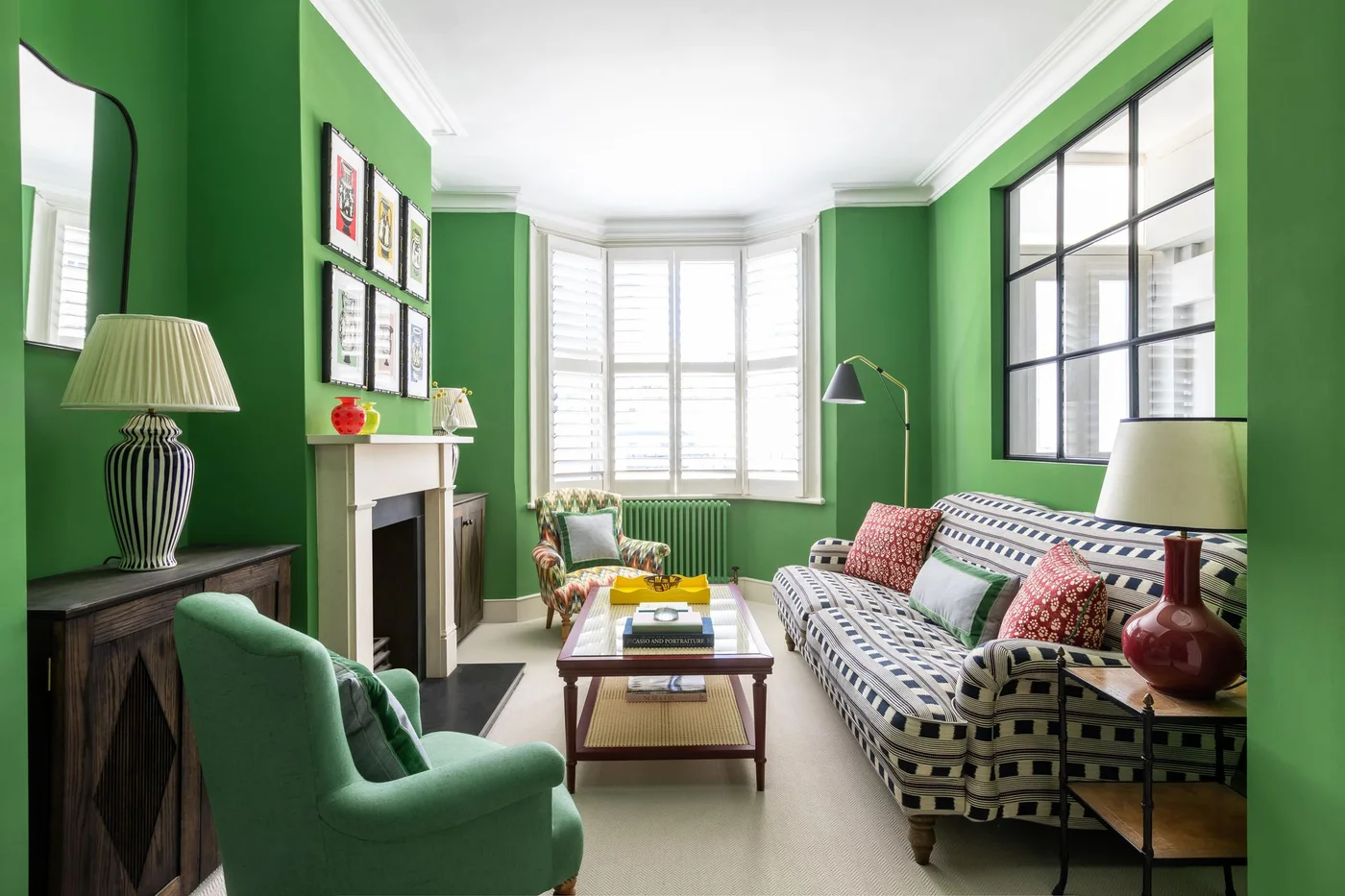 Bright green walls surround patterned seating, a green armchair and a pale fireplace beneath a light ceiling