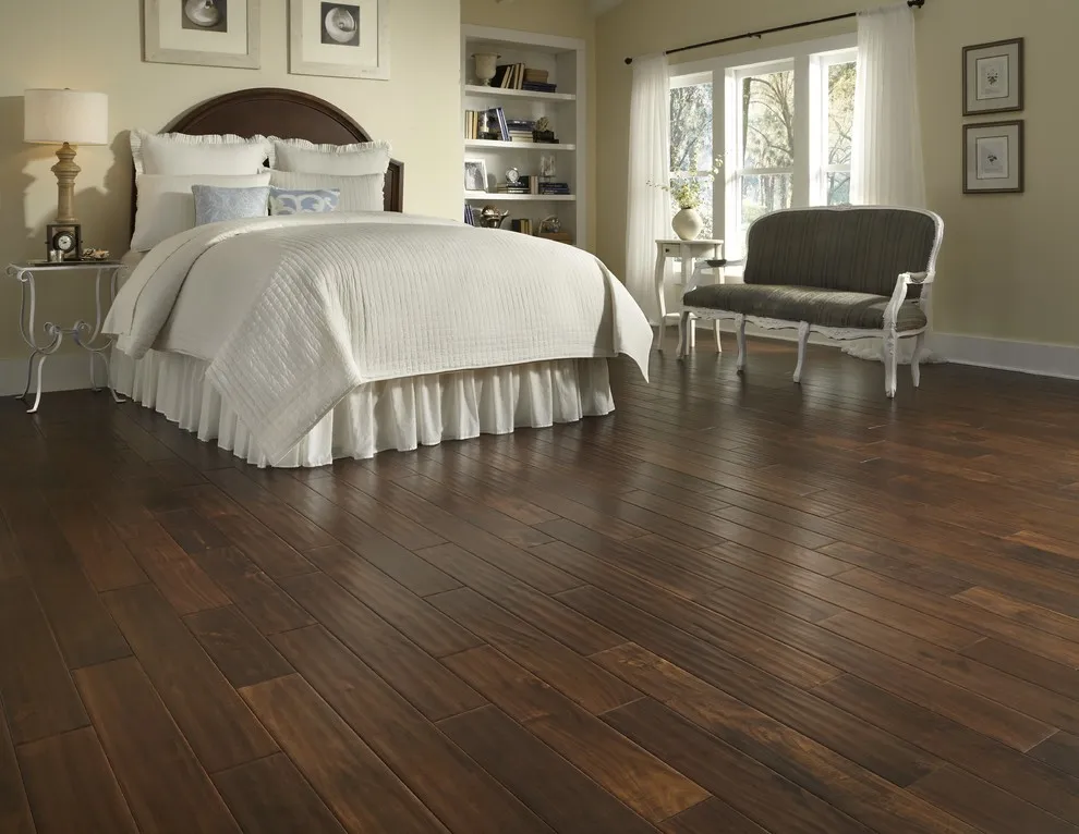 A dark brown wood floor surrounds a pale traditional bed and bench