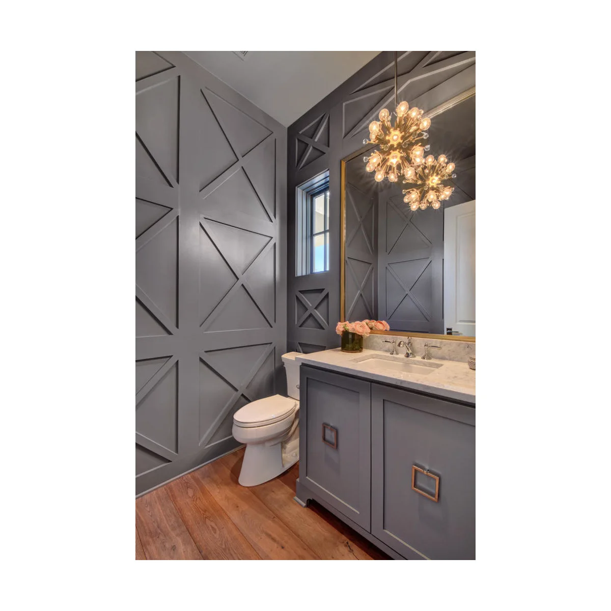 Dark gray X-pattern wall paneling in a compact powder room beside a matching vanity