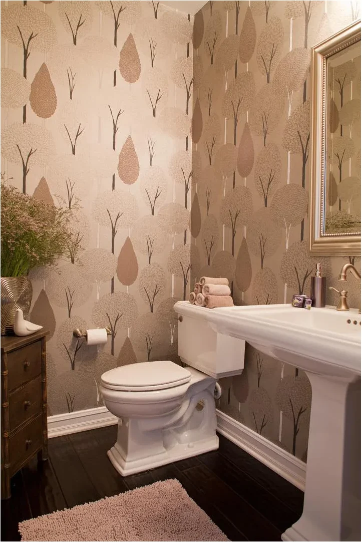 Pedestal sink in a small patterned bathroom with a slim wooden chest beside it