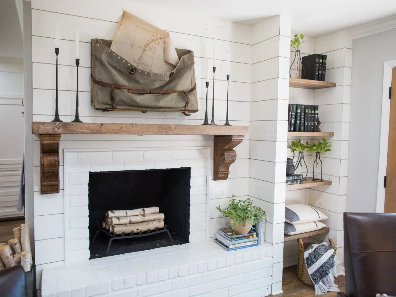 Timber corbels support a mantel over white brick beside open shelves on a white boarded wall.