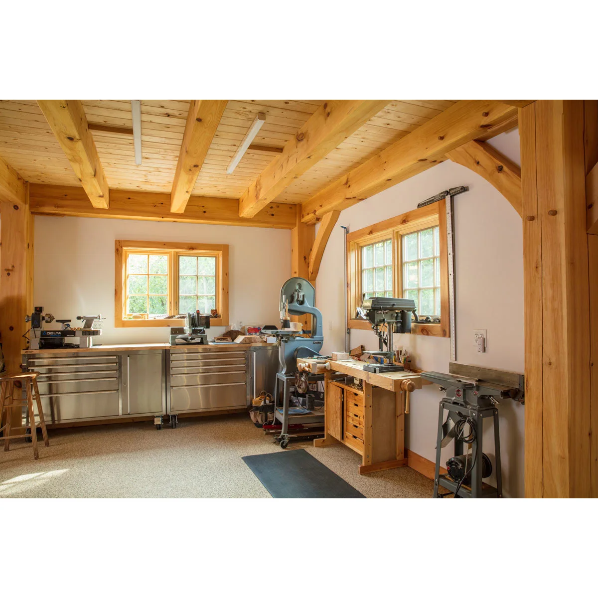 Timber-framed wood workshop with metal drawer cabinets, a wooden bench and several small woodworking machines.