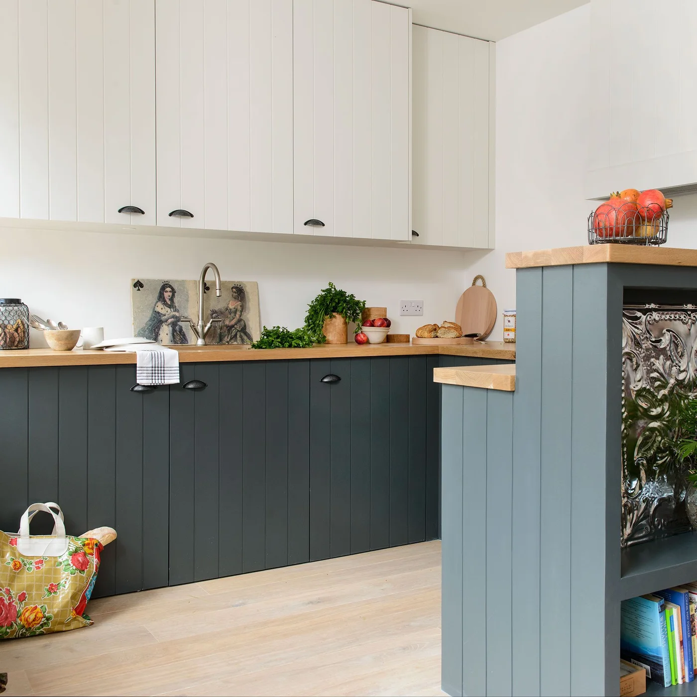 White upper cabinets and blue-gray lower cabinets share vertical grooves and dark cup handles