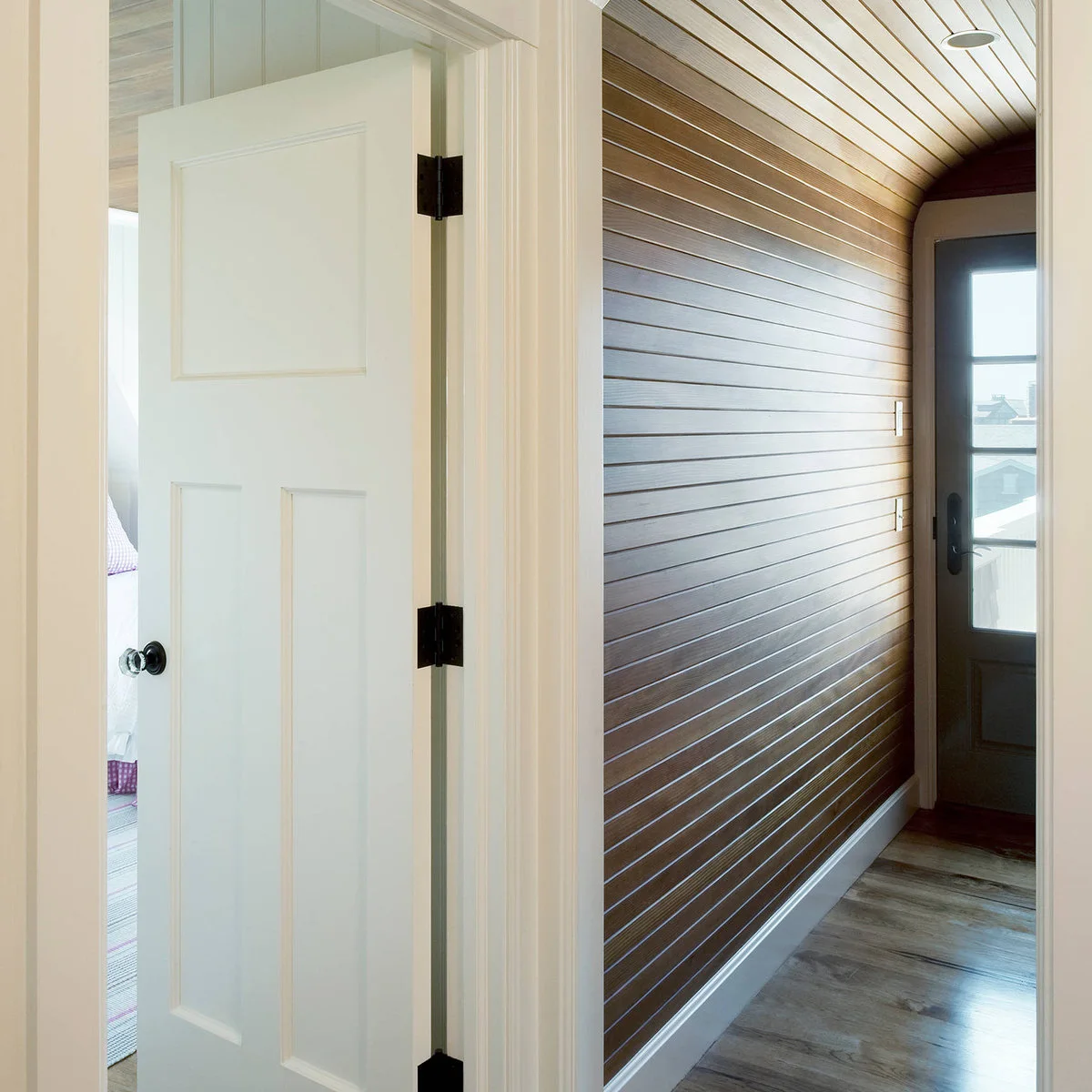 Narrow brown wall boards continuing around a curved junction beside a glazed door