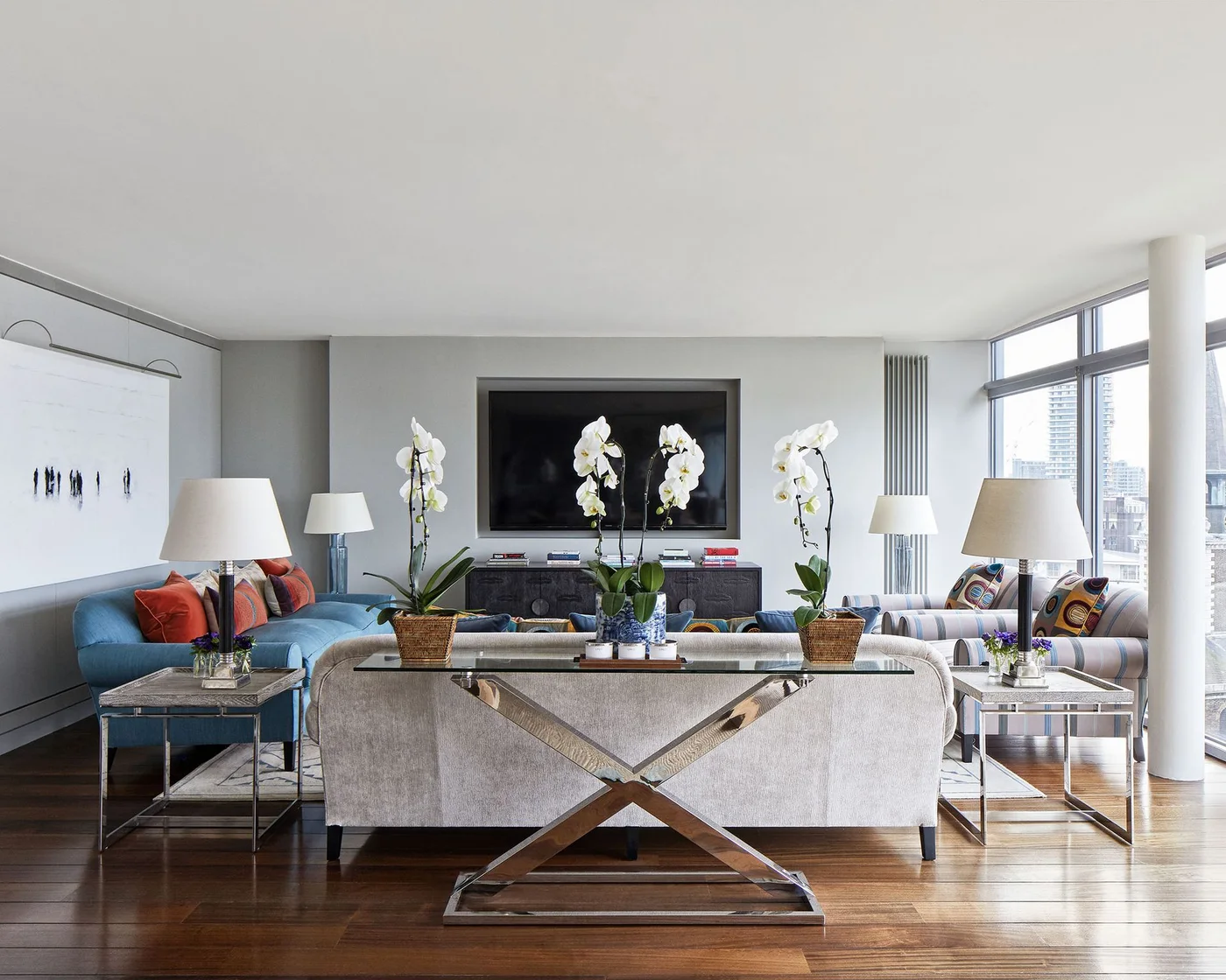 Apartment living room with TV above a dark sideboard and blue sofa along one wall