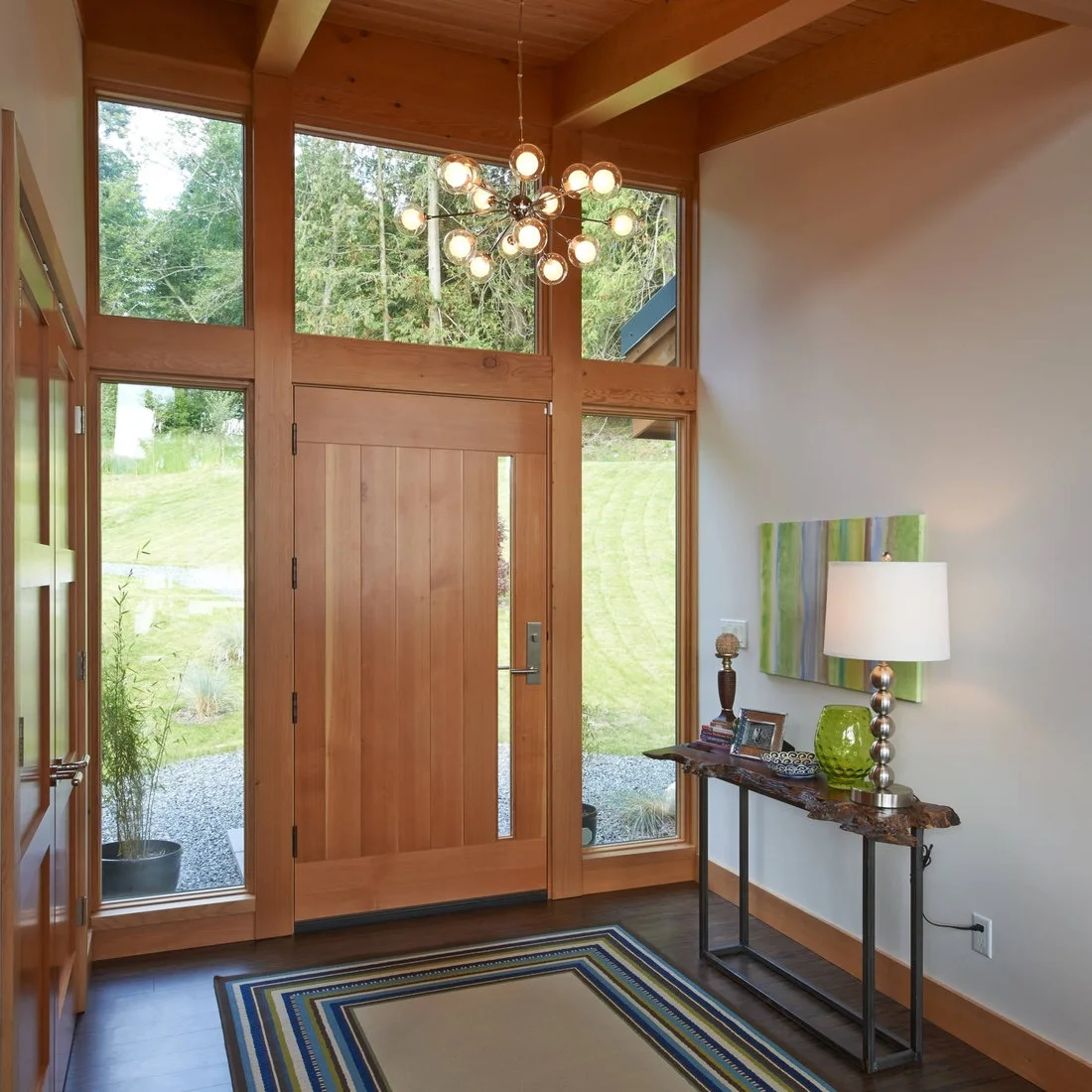 A slim live edged wood console beside a pale timber entrance door and tall glazing