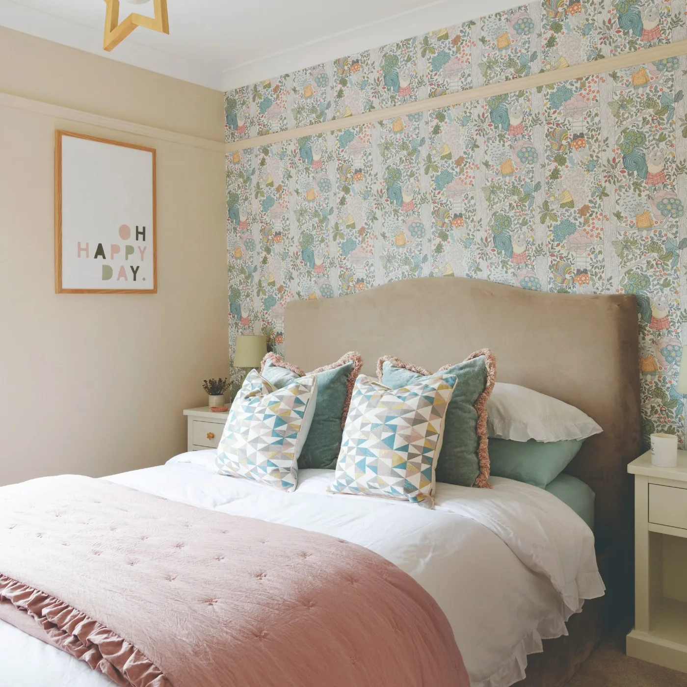 Pastel floral wallpaper behind a curved beige headboard beside a peach wall and geometric cushions.