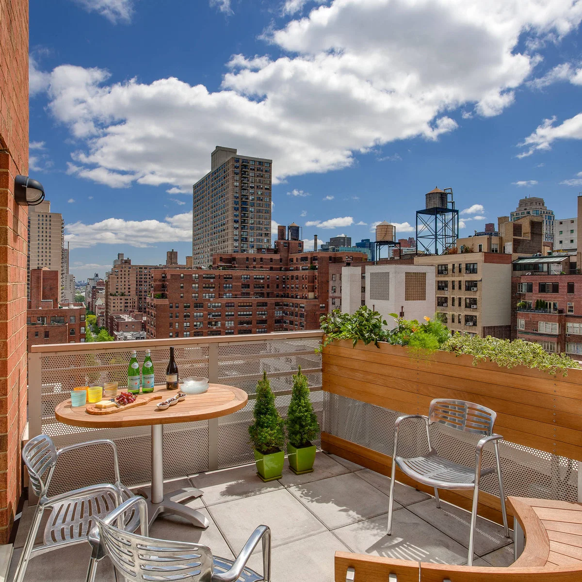 City apartment balcony with round pedestal table, metal chairs and long planter