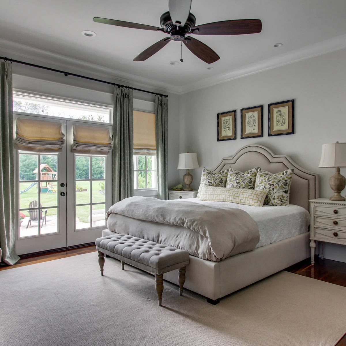 Short gray tufted bench centered in front of a pale bed near glazed doors