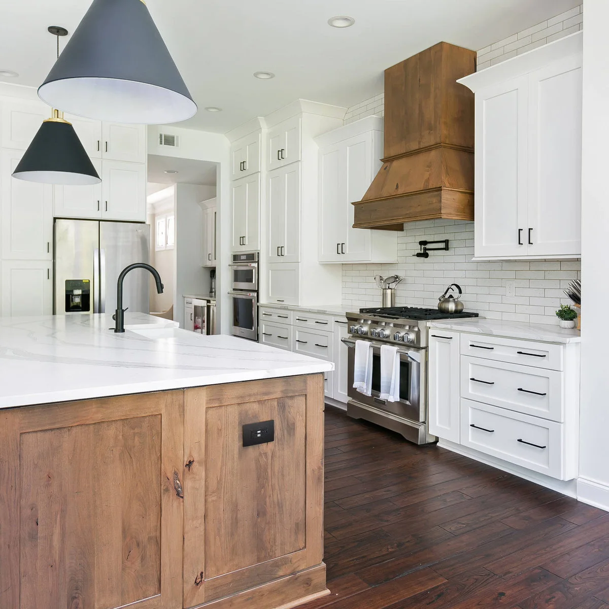 Wood kitchen island base echoing a large wood range hood in a white kitchen