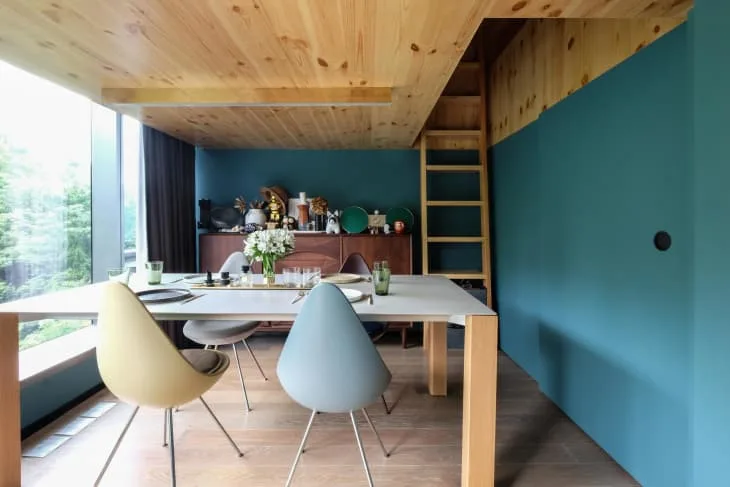 Small pale flowers on a set rectangular dining table with mixed pastel chairs against blue walls