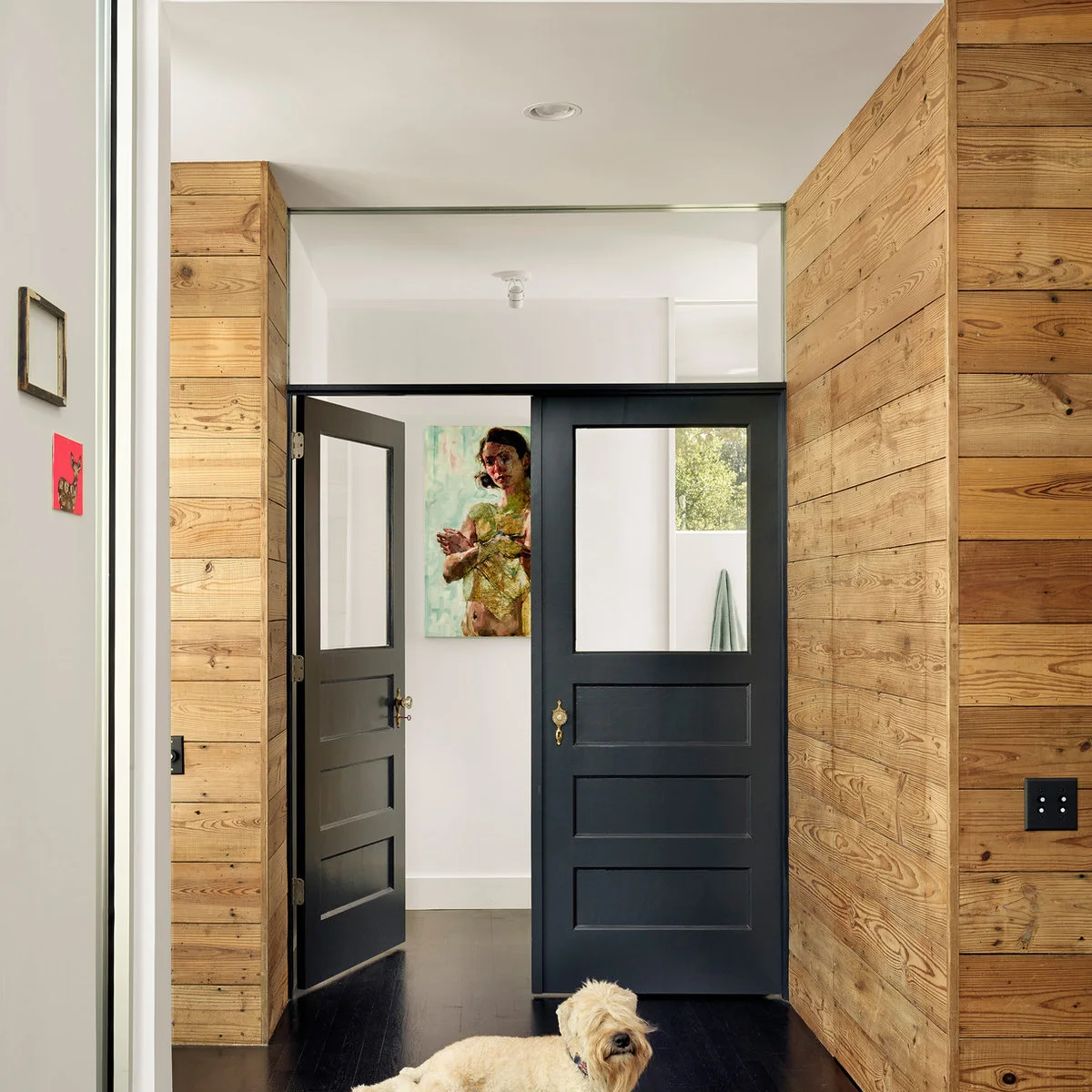 Horizontal natural wood boards flanking dark glazed doors in an interior passage
