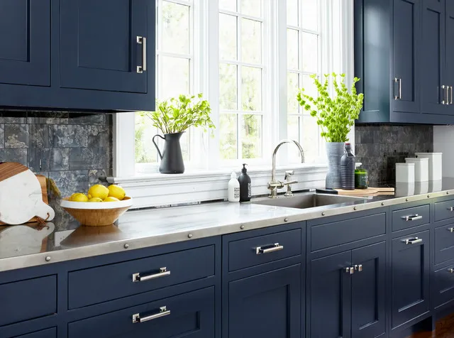 Blue drawers with silver-toned handles sit beneath a pale counter beside bright windows.