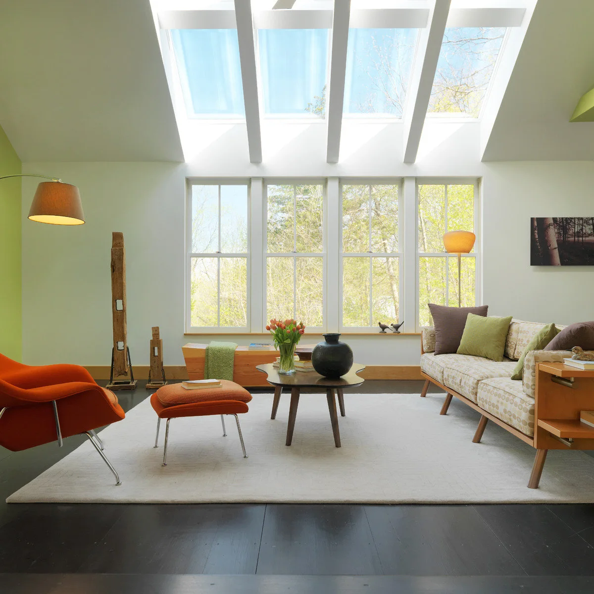Burnt orange lounge chair and footstool on a pale rug above a dark gray floor in a bright sitting room.