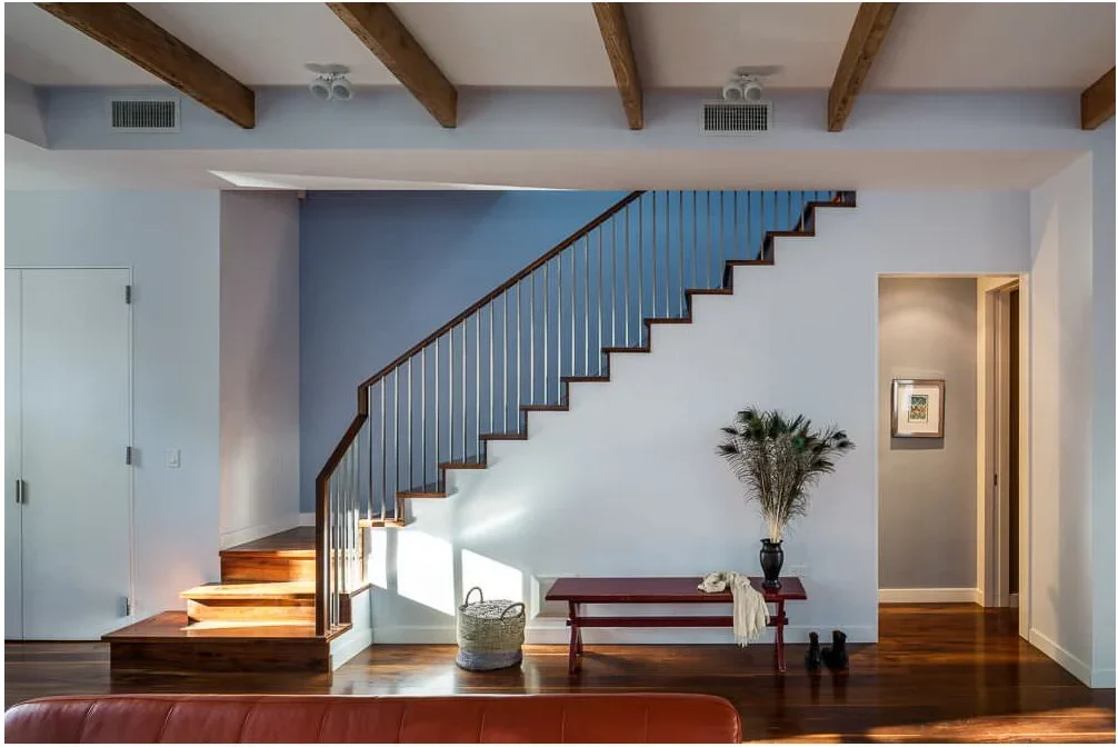 A pale blue wall follows the sloping stair line above a white lower section and dark bench.