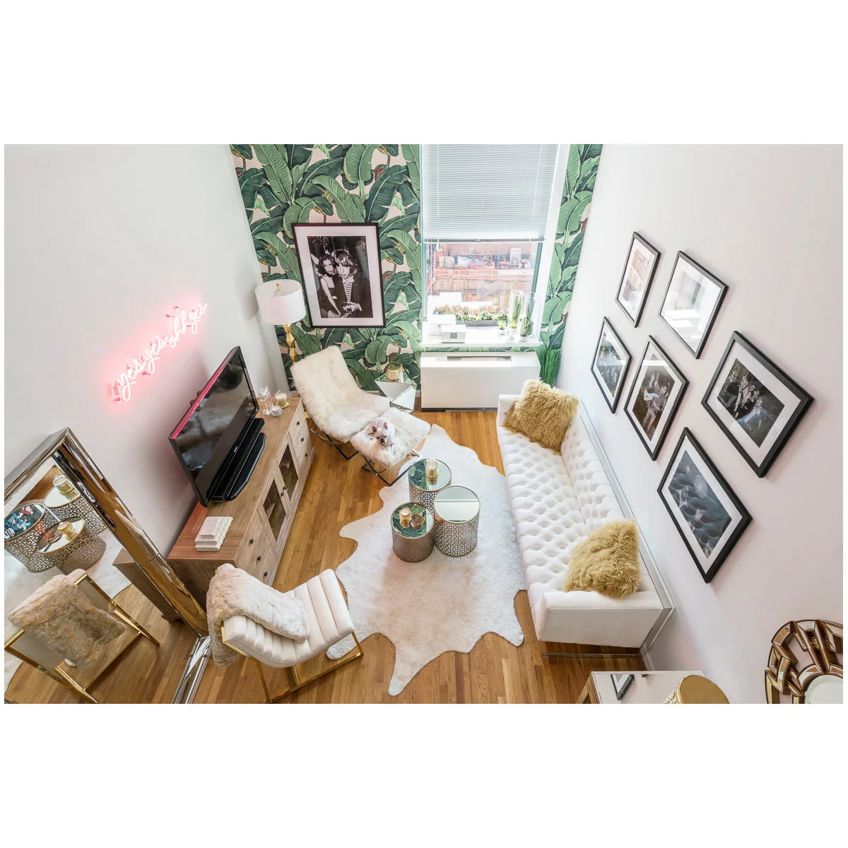 Narrow white living room with a white sofa, two light chairs and small round tables
